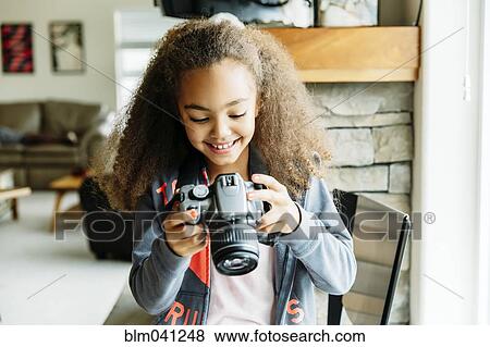 Mixed race girl using camera in living room View Large Photo Image Stock Photo - Mixed race girl using camera in living room. Fotosearch