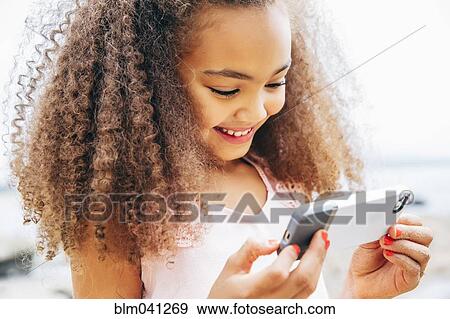 Mixed race girl using cell phone on beach View Large Photo Image Stock Photo - Mixed race girl using cell phone on beach. Fotosearch