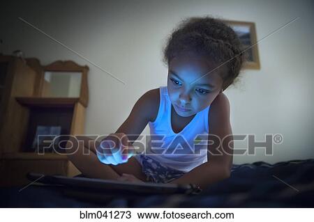 Stock Image - Mixed race girl using digital tablet. Fotosearch