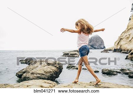 Stock Image - Mixed race girl walking on beach. Fotosearch