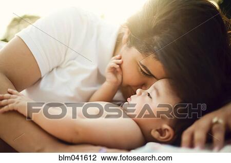 Stock Image - Mixed race mother nuzzling baby. Fotosearch