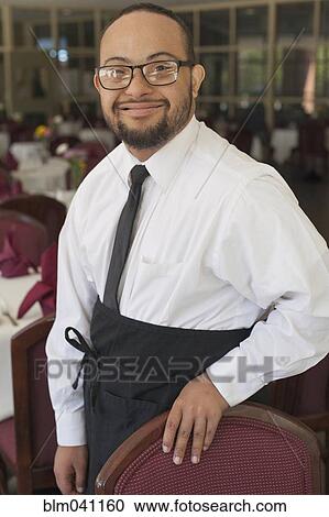 Stock Image - Mixed race server with down syndrome smiling in restaurant. Fotosearch