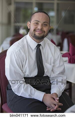 Stock Image - Mixed race server with down syndrome smiling in restaurant. Fotosearch