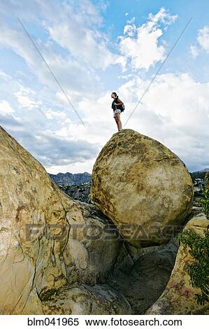 Stock Photography - Mixed race woman climbing rock formation. Fotosearch