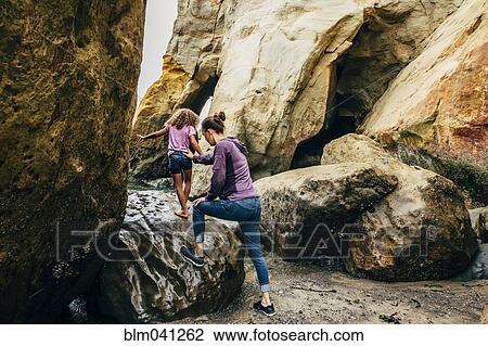 Mother and daughter climbing on beach rocks View Large Photo Image Stock Image - Mother and daughter climbing on beach rocks. Fotosearch