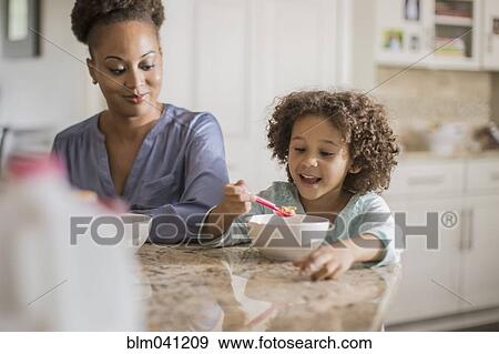 Mother and daughter eating at table View Large Photo Image Stock Photo - Mother and daughter eating at table. Fotosearch