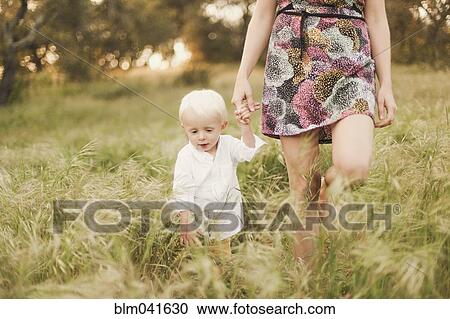 Stock Image - Mother and son walking in field. Fotosearch