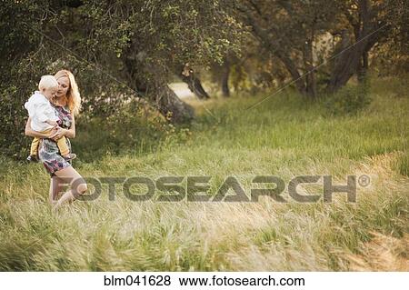 Mother carrying son in field View Large Photo Image Stock Photo - Mother carrying son in field. Fotosearch