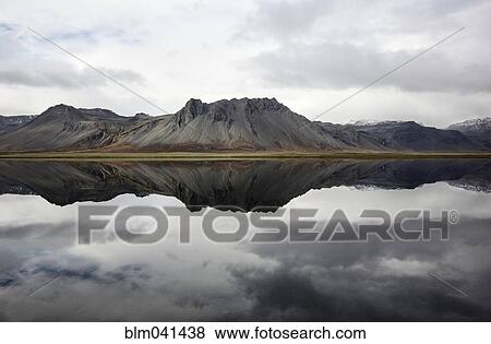 Mountains reflecting in still lake View Large Photo Image Stock Photo - Mountains reflecting in still lake. Fotosearch