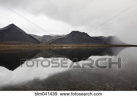 Mountains reflecting in still lake View Large Photo Image Stock Photo - Mountains reflecting in still lake. Fotosearch
