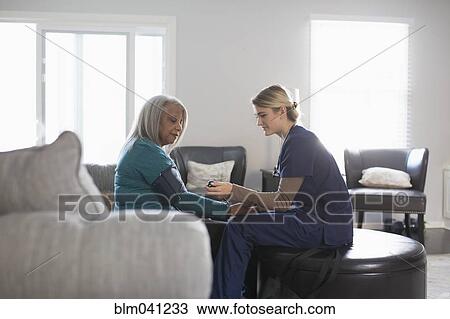 Nurse taking patient blood pressure in living room View Large Photo Image Stock Image - Nurse taking patient blood pressure in living room. Fotosearch