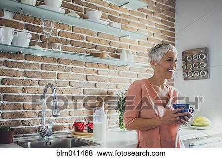 Older Caucasian woman having coffee in kitchen View Large Photo Image Stock Photo - Older Caucasian woman having coffee in kitchen. Fotosearch