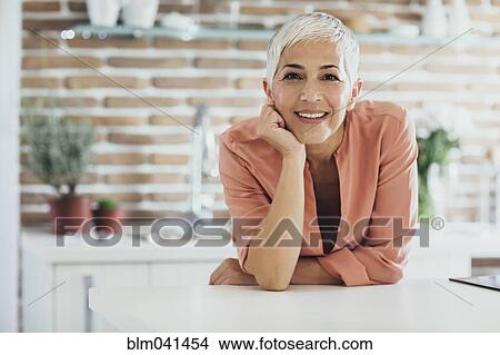 Picture - Older Caucasian woman smiling in kitchen. Fotosearch