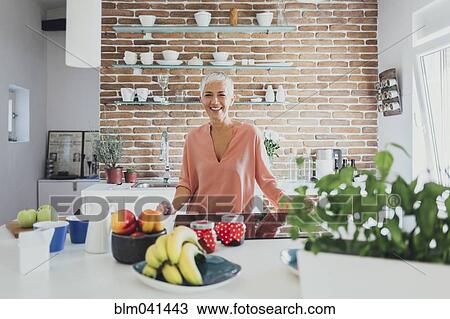 Stock Image - Older Caucasian woman smiling in kitchen. Fotosearch