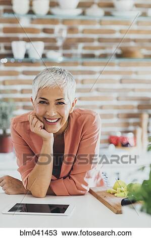 Stock Image - Older Caucasian woman smiling in kitchen. Fotosearch