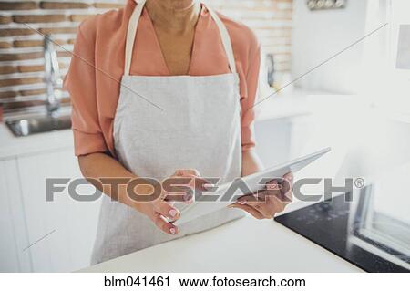 Older Caucasian woman using digital tablet in kitchen View Large Photo Image Stock Image - Older Caucasian woman using digital tablet in kitchen. Fotosearch