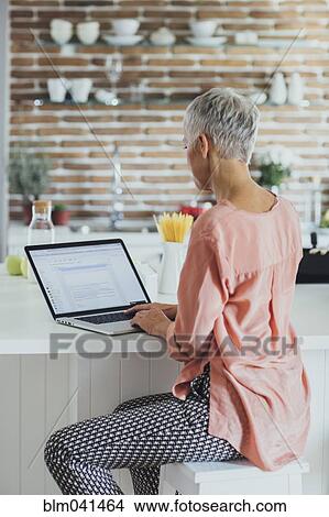Older Caucasian woman using laptop in kitchen View Large Photo Image Picture - Older Caucasian woman using laptop in kitchen. Fotosearch