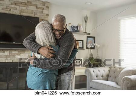 Older couple hugging in living room View Large Photo Image Stock Photograph - Older couple hugging in living room. Fotosearch