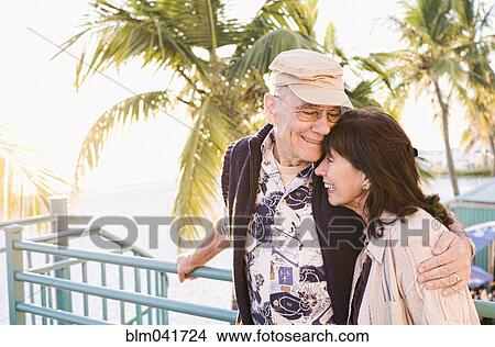Picture - Older couple hugging outdoors. Fotosearch