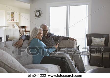 Older couple using digital tablet on sofa View Large Photo Image Stock Image - Older couple using digital tablet on sofa. Fotosearch