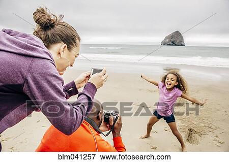 Parents photographing daughter on beach View Large Photo Image Stock Photo - Parents photographing daughter on beach. Fotosearch