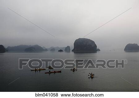 Stock Photo - People paddling canoes in Ha Long Bay, Quang Ninh Province, Vietnam. Fotosearch