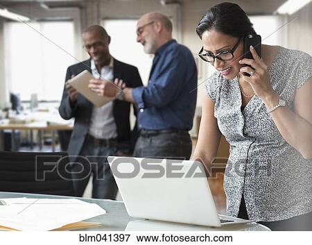 Stock Photo - Pregnant businesswoman talking on cell phone in office. Fotosearch