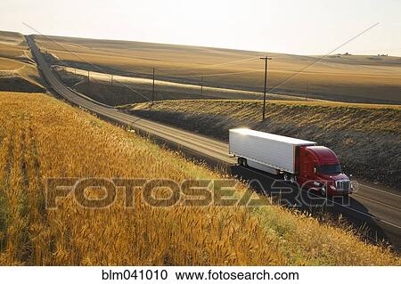 Stock Image - Truck driving on remote road. Fotosearch