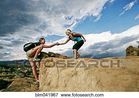 Woman helping friend climb rock formation View Large Photo Image Stock Photo - Woman helping friend climb rock formation. Fotosearch