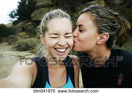 Woman kissing cheek of friend outdoors View Large Photo Image Stock Image - Woman kissing cheek of friend outdoors. Fotosearch