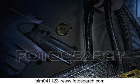 Woman placing gun in purse View Large Photo Image Stock Image - Woman placing gun in purse. Fotosearch