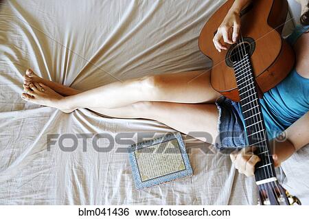 Woman playing guitar on bed View Large Photo Image Stock Photograph - Woman playing guitar on bed. Fotosearch