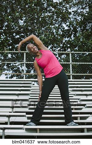 Stock Photo - Woman stretching on bleachers. Fotosearch