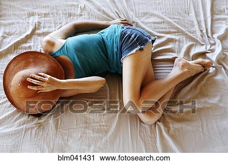 Woman with sun hat laying on bed View Large Photo Image Stock Image - Woman with sun hat laying on bed. Fotosearch
