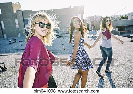 Stock Photo - Women holding hands on urban rooftop. Fotosearch
