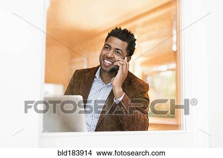 Picture - African American businessman talking on cell phone in office. Fotosearch