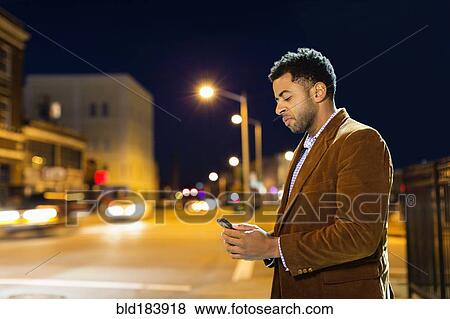 Stock Photo - African American businessman using cell phone outdoors. Fotosearch