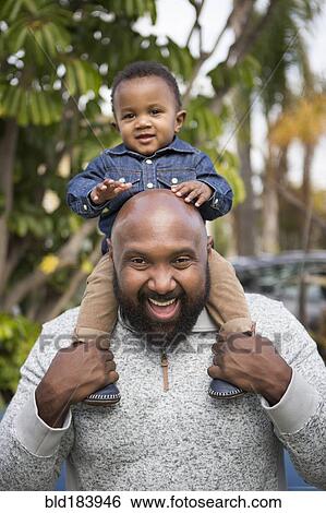 Stock Photograph - African American father carrying son on shoulders. Fotosearch