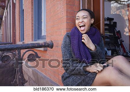 Stock Image - African American woman laughing in window. Fotosearch