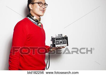 Stock Photograph - Asian photographer holding vintage camera. Fotosearch