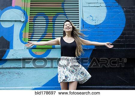 Stock Photo - Asian woman cheering with arms outstretched. Fotosearch