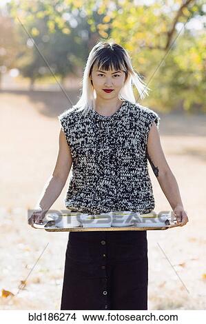 Picture - Asian woman holding platter of soup outdoors. Fotosearch