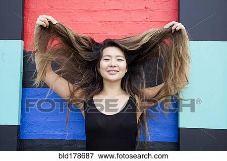 Asian woman playing with hair View Large Photo Image Stock Photo - Asian woman playing with hair. Fotosearch