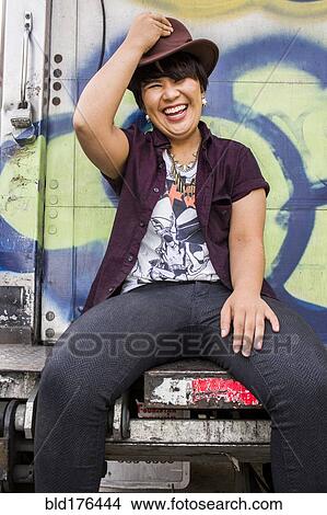 Picture - Asian woman sitting on graffiti truck. Fotosearch