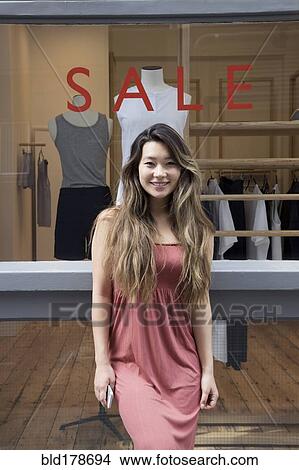 Picture - Asian woman standing outside store. Fotosearch