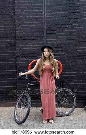 Asian woman standing with bicycle View Large Photo Image Stock Photography - Asian woman standing with bicycle. Fotosearch