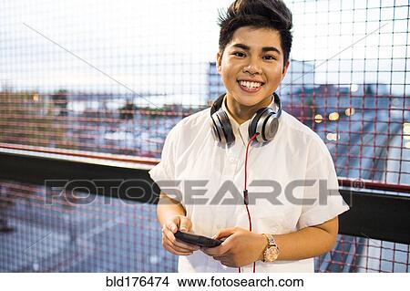 Picture - Asian woman using cell phone outdoors. Fotosearch