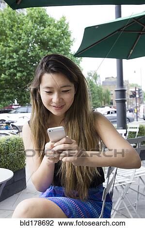 Stock Image - Asian woman using cell phone outdoors. Fotosearch
