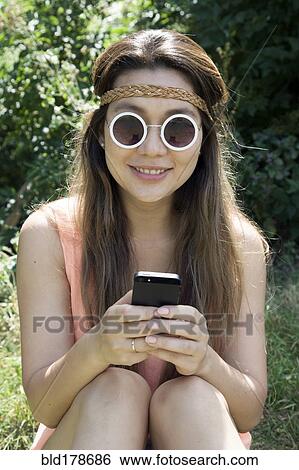 Stock Photograph - Asian woman using cell phone outdoors. Fotosearch