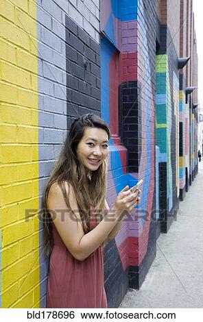 Asian woman using cell phone outdoors View Large Photo Image Stock Photograph - Asian woman using cell phone outdoors. Fotosearch